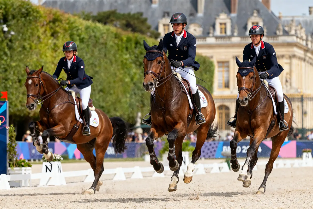 Cavaliers en compétition de saut d'obstacles pour l'équitation JO 2024 devant un château