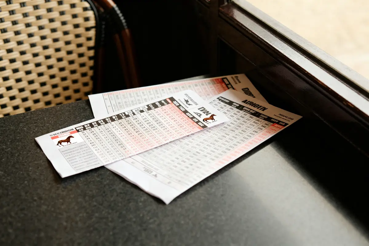 Feuilles imprimées sur table montrant les résultats des courses hippiques avec probabilités affichées