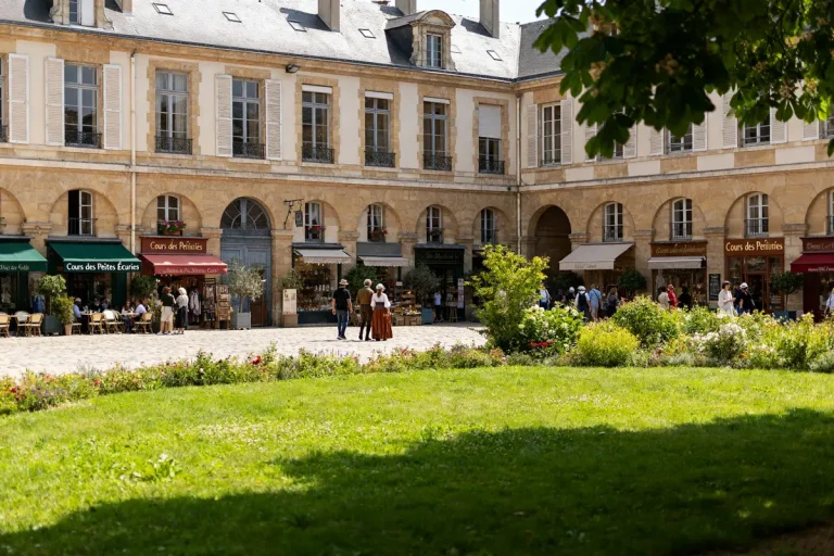 Personnes se promenant devant boutiques historiques du cours des Petites Écuries à Paris