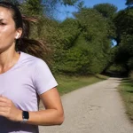 Une femme court sur un chemin forestier, illustrant l'endurance physique en plein air